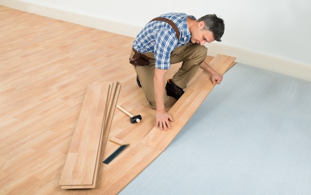 Carpenter installing new laminated wooden floor
