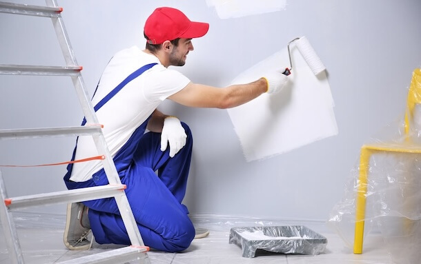 worker painting wall in a room